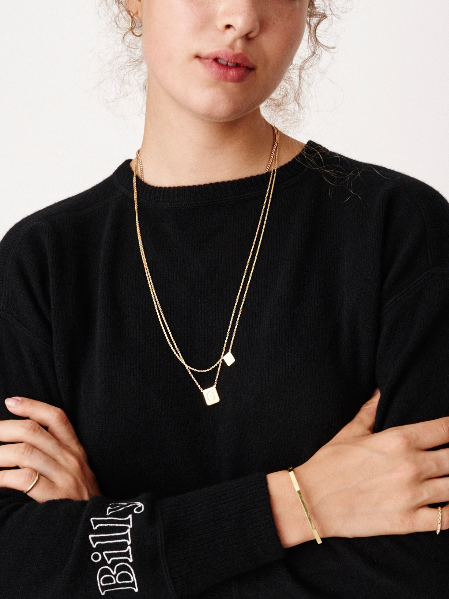 Young girl wearing two personalized gold tag necklaces by love billy and a billy sweatshirt.