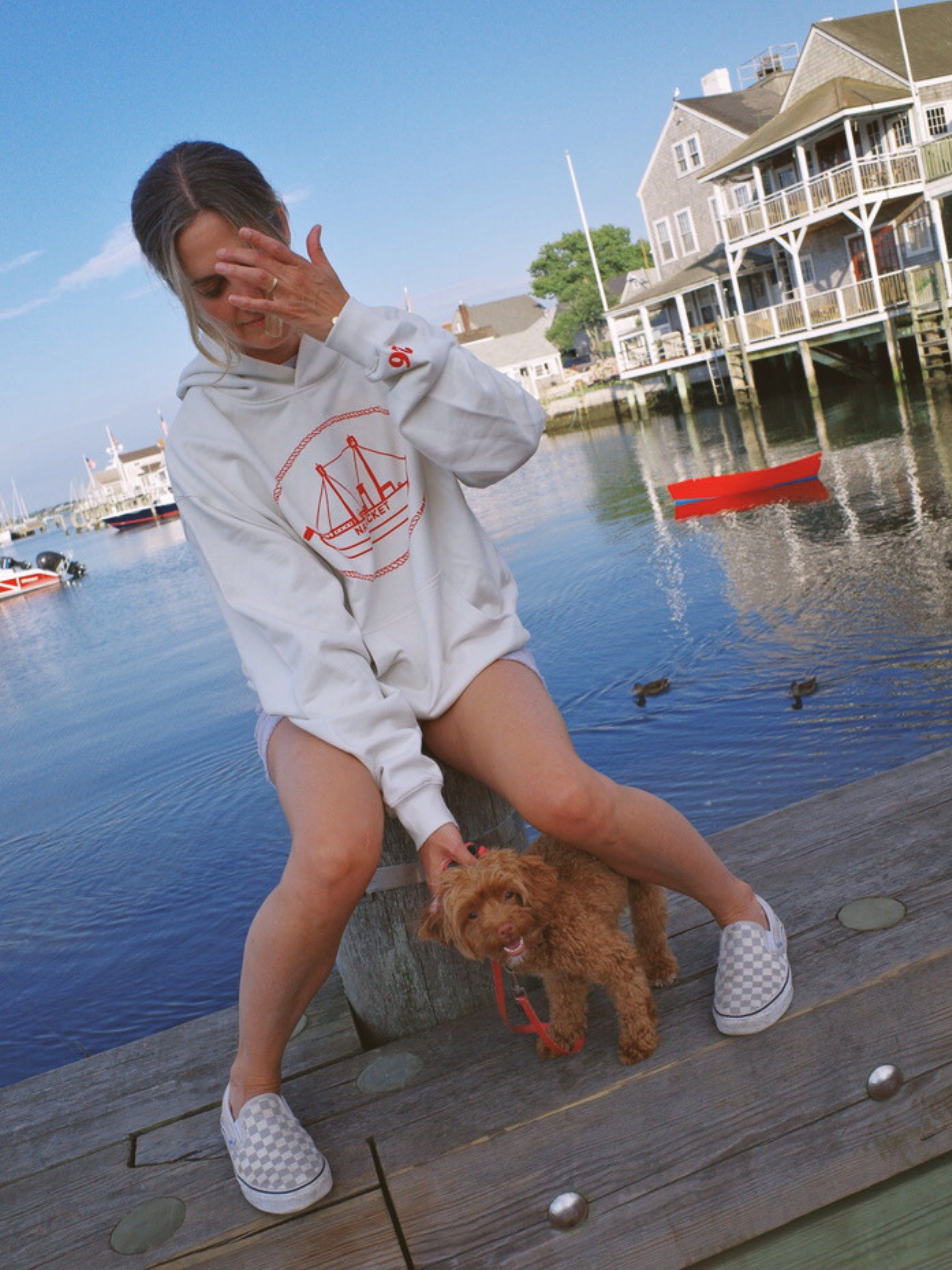 young girl wearing the nantucket hoodie by love billy and holding a dog. Sweatshirt printed with a red US nantucket light ship and a 26 embroidered on the sleeve.