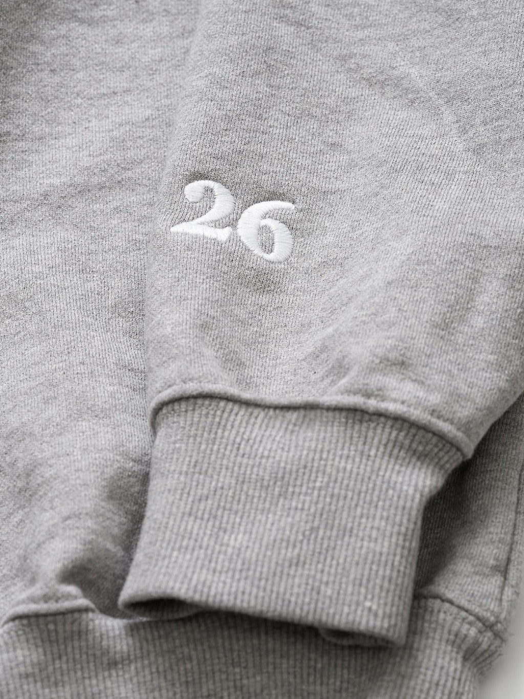 closeup of the "26" embroidery on the sleeve of the heather grey crewneck unisex sweatshirt by love billy.
