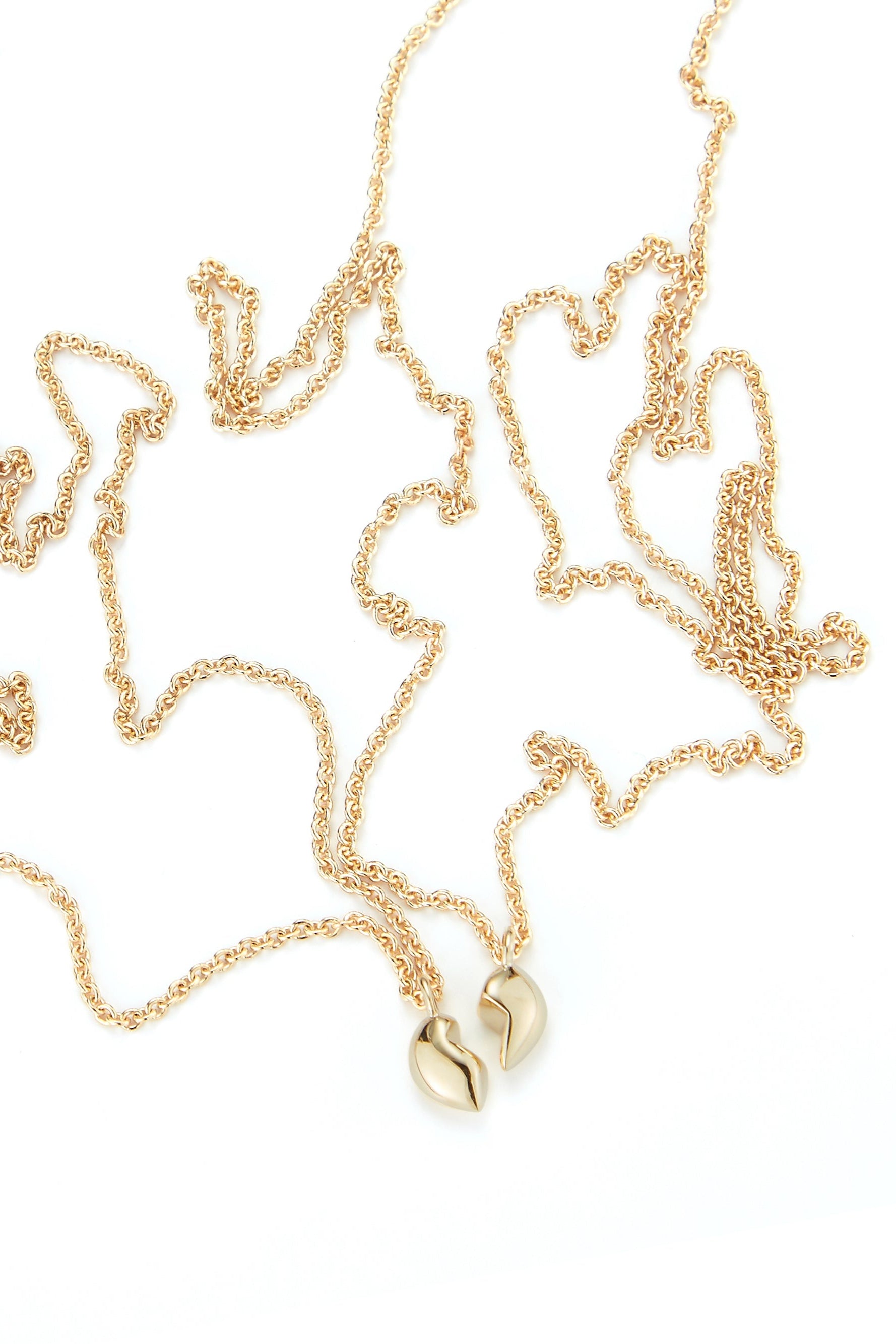 two halves of the gold split heart necklace by love billy laid next to each other.