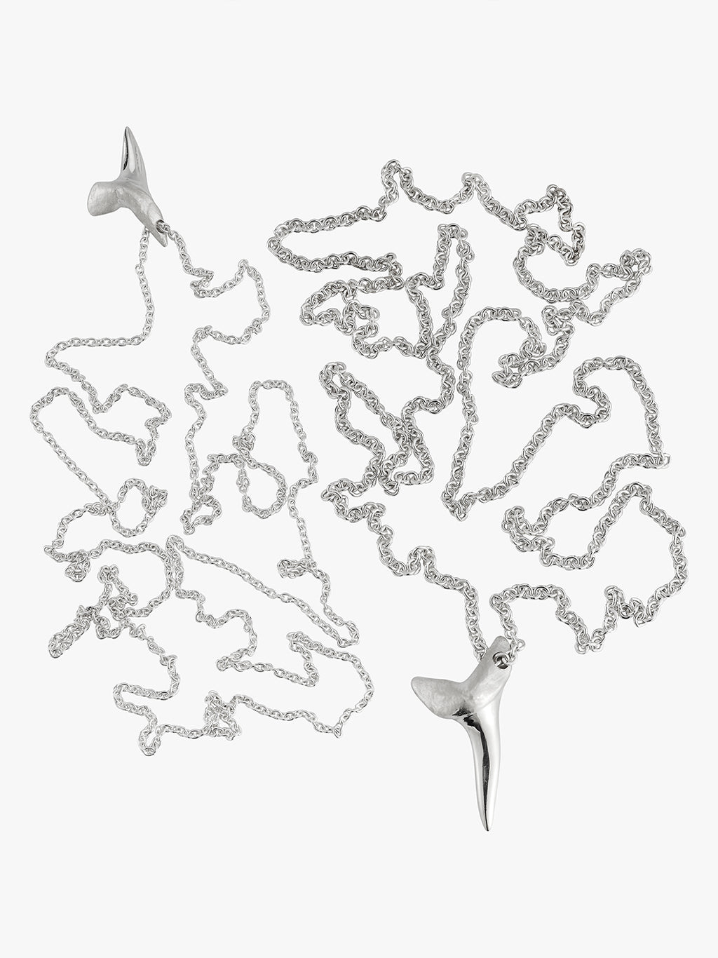 two silver shark tooth necklaces by love billy lead next to each other. one on a cable chain and the other on a wheat chain.