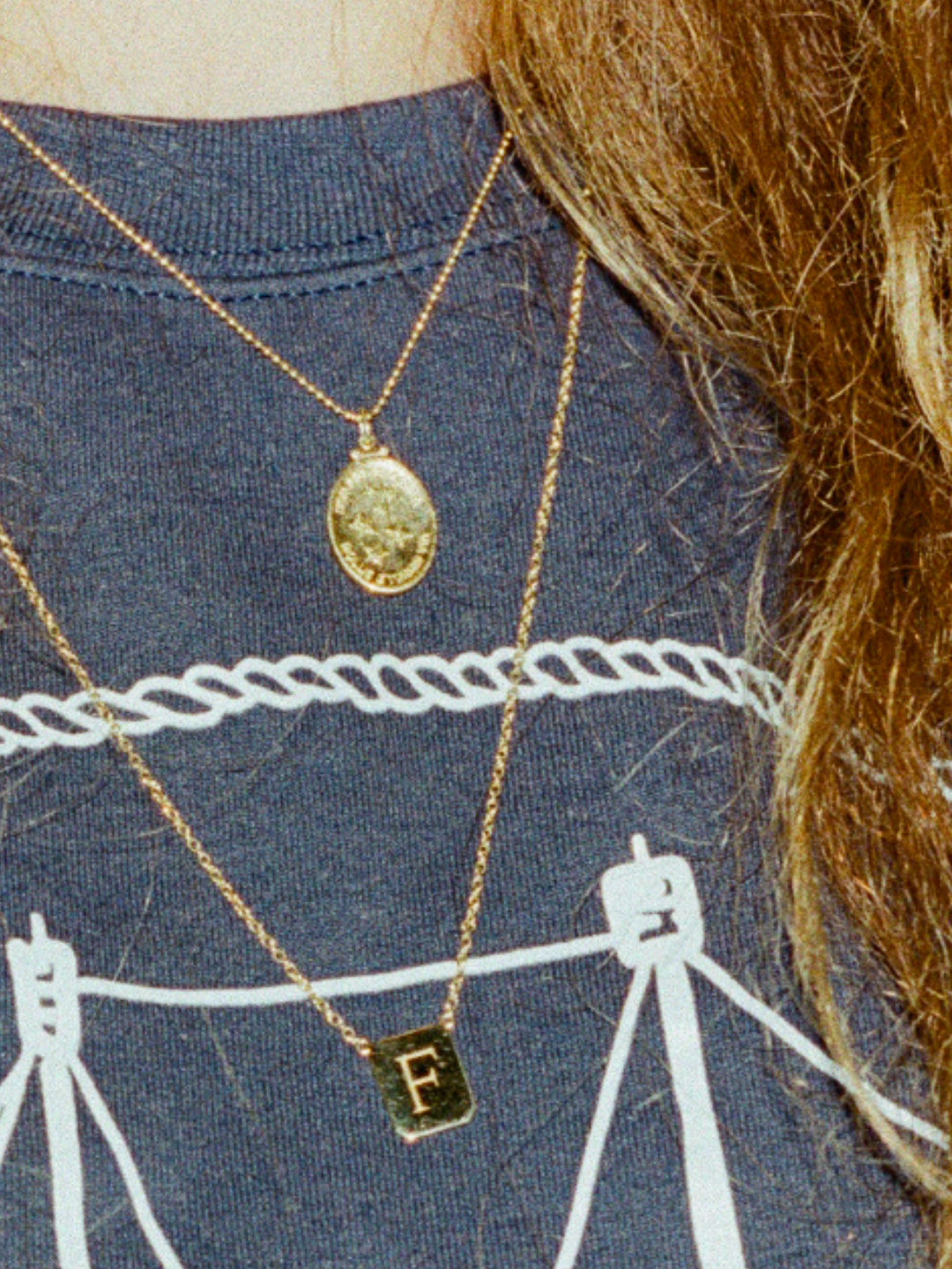 Girl wearing washed nantucket crewneck with two Gold necklaces. One is the gold stars medallion and the other is the letter 'F' tag medallion. Crewneck and necklaces made by Love Billy in NYC.