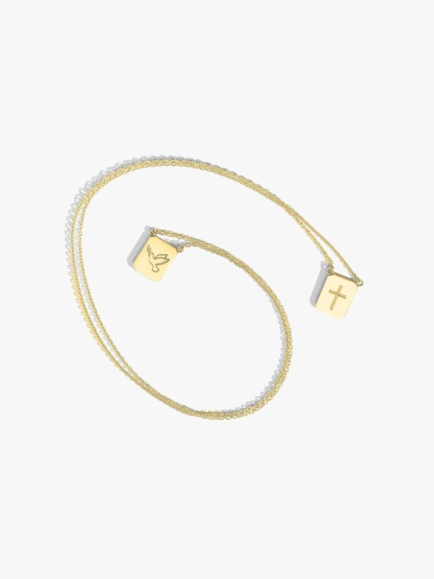 Gold tag necklace with two tags. One engraved with a cross and one with a dove. Made by Love Billy.