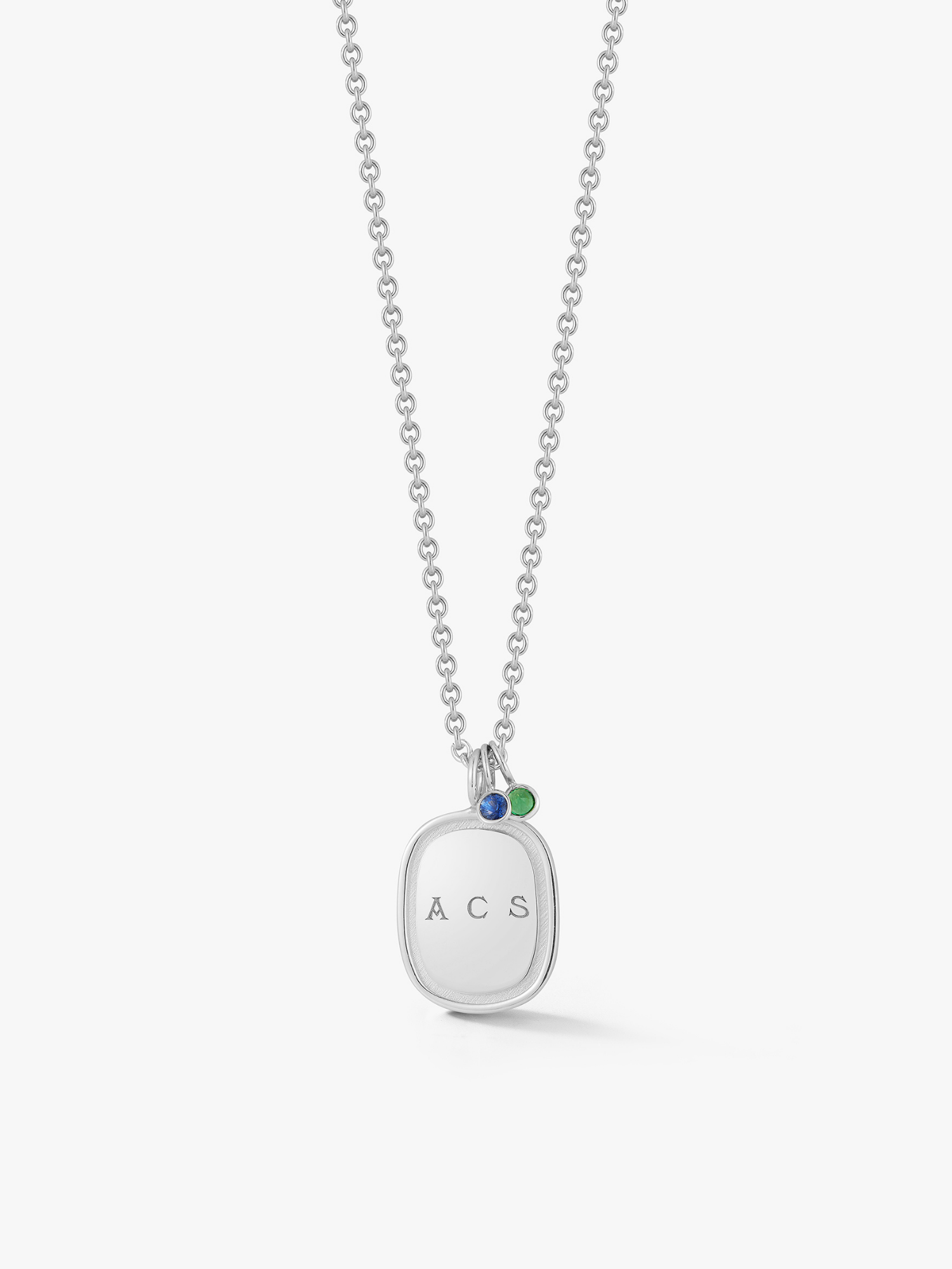 Silver oblong necklace engraved with "ACS" with two gemstone drops. One a sapphire and one a emerald. Made by Love Billy.
