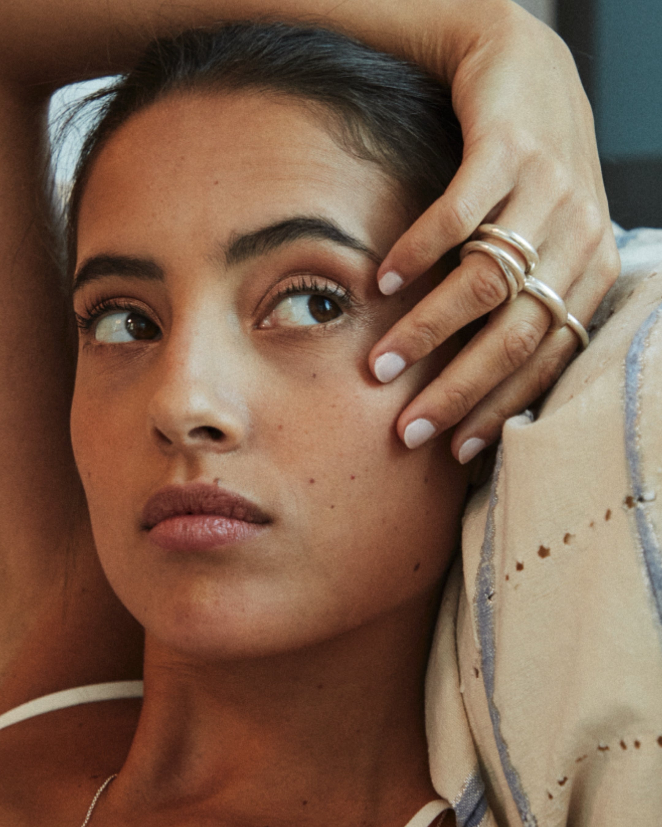 close up of a women with a white and blue tapestry behind here wearing a mini, regular, jumbo, and linked carousel rings on her fingers