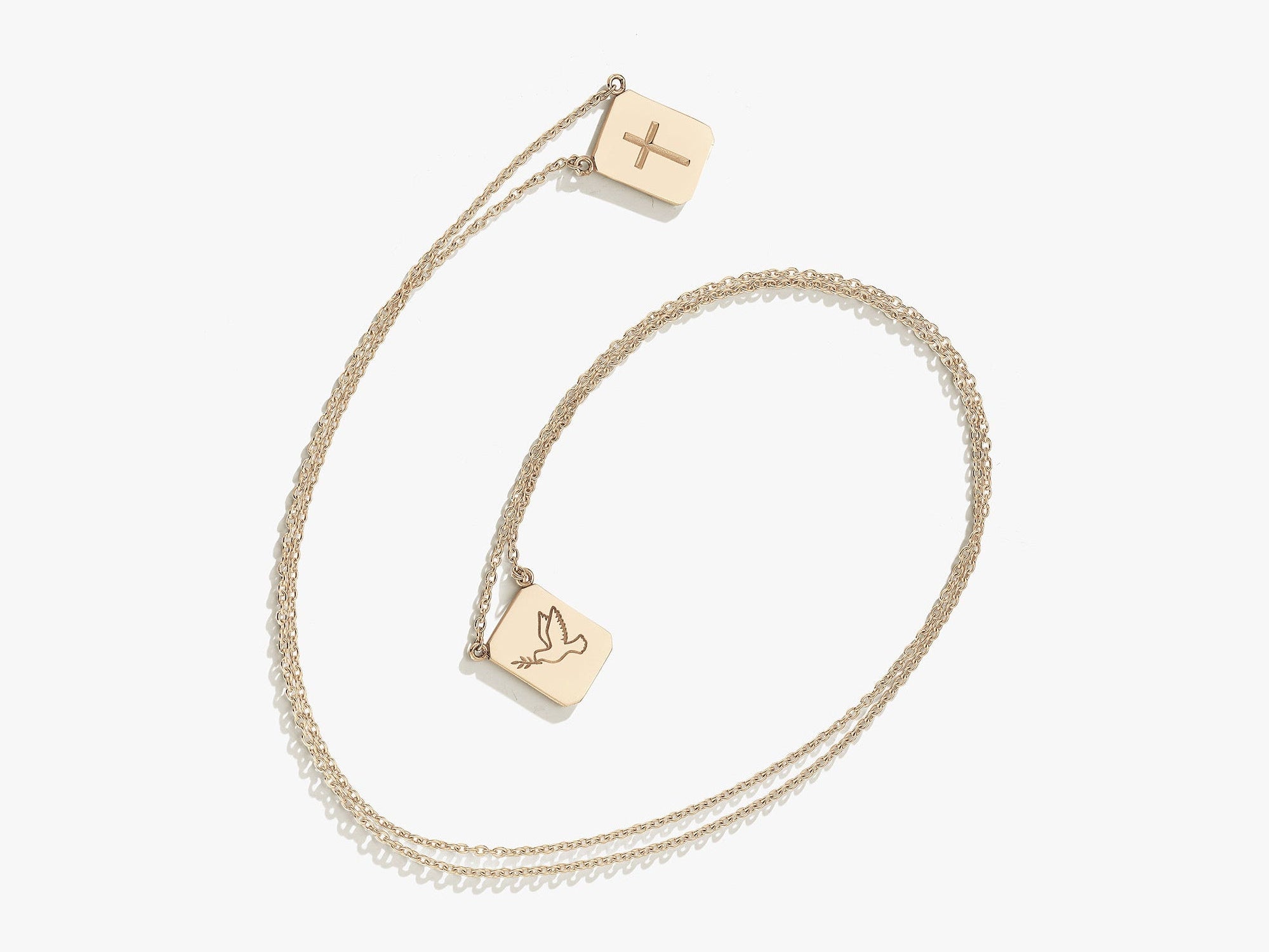 Gold necklace with two pendants on a white background. one pendant has a cross, the other has a dove