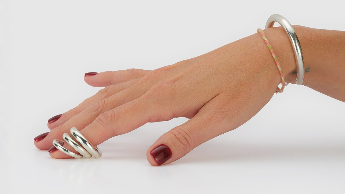 Hand wearing multiple silver rings with 'Billy!' text above on a white background
