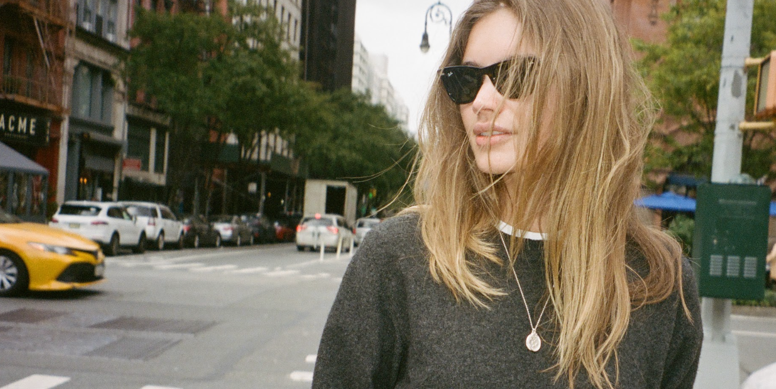 homepage for love billy jewelry. image of girl on nyc street wearing oval latin medallion pendants