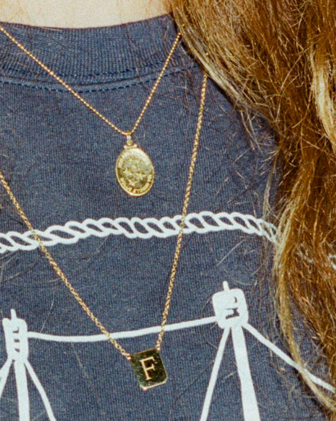 Girl wearing washed nantucket crewneck with two Gold necklaces. One is the gold stars medallion and the other is the letter 'F' tag medallion. Crewneck and necklaces made by Love Billy in NYC. 