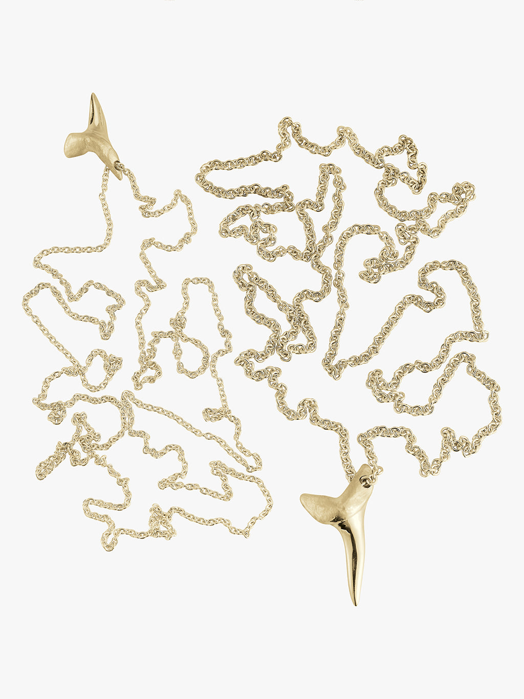 two gold shark tooth necklaces by love billy laid next to each other. one on a a cable chain and the other on a wheat chain.