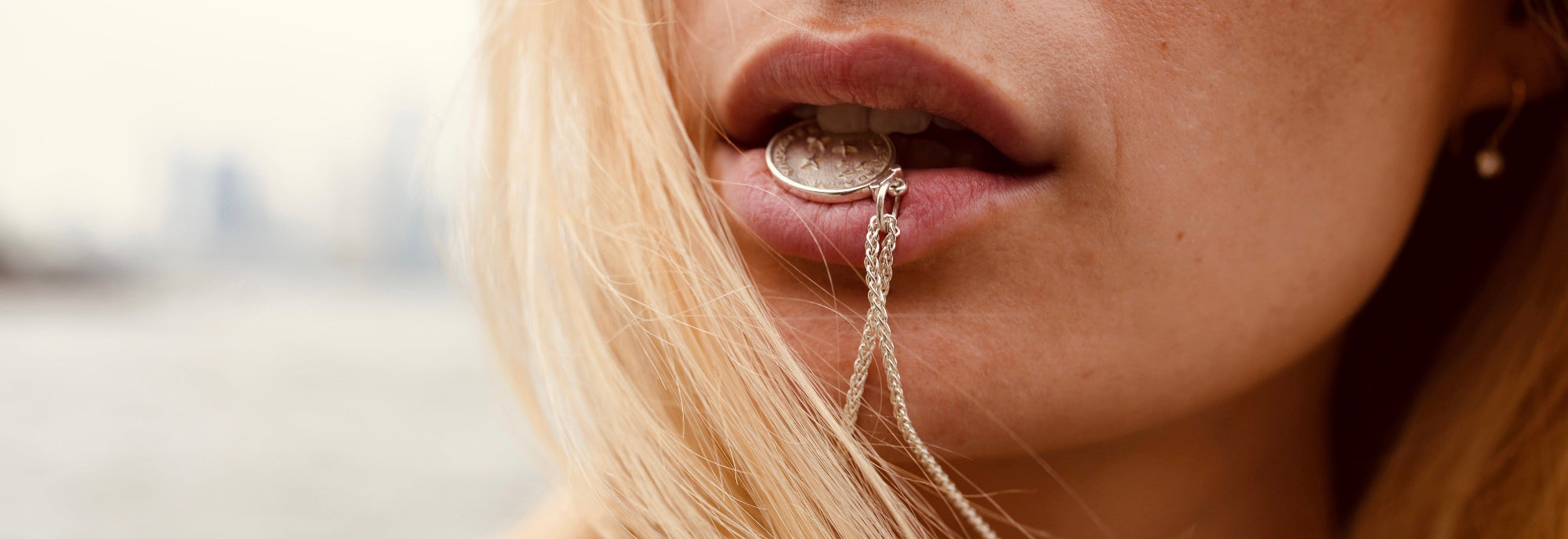 blond girl biting on a love billy pendant