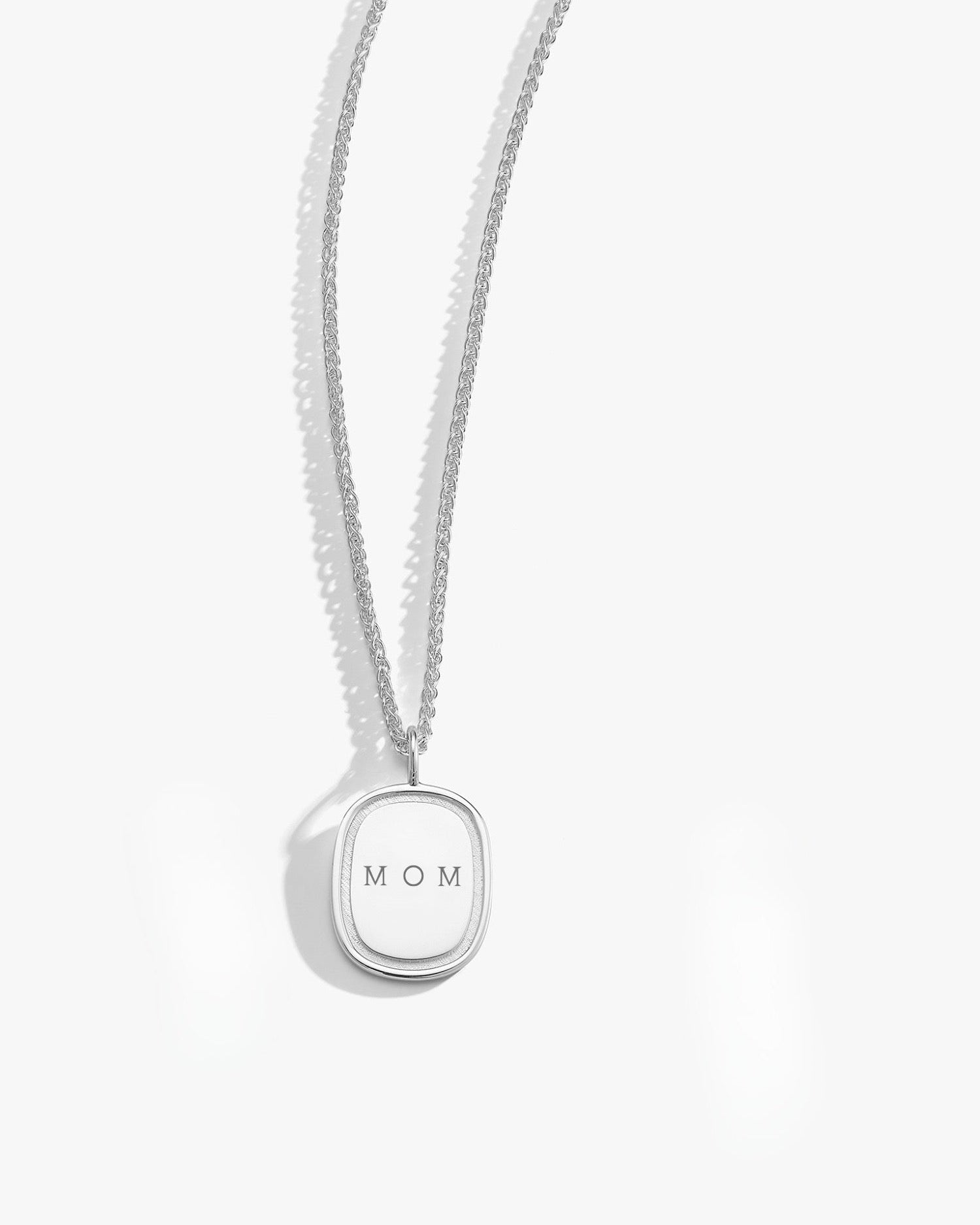 Silver necklace with a pendant that reads 'MOM' on a white background