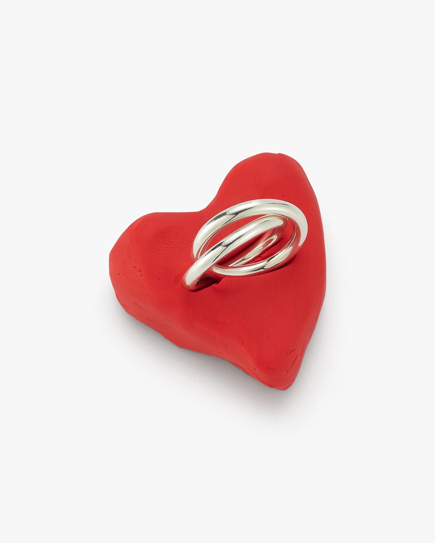 linked silver carousel ring shown in a red clay heart
