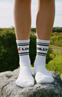 love billy tube socks on feet standing on a rock with an outdoor background. classic tube socks. a good new york city souvenir that you won't find on canal street.