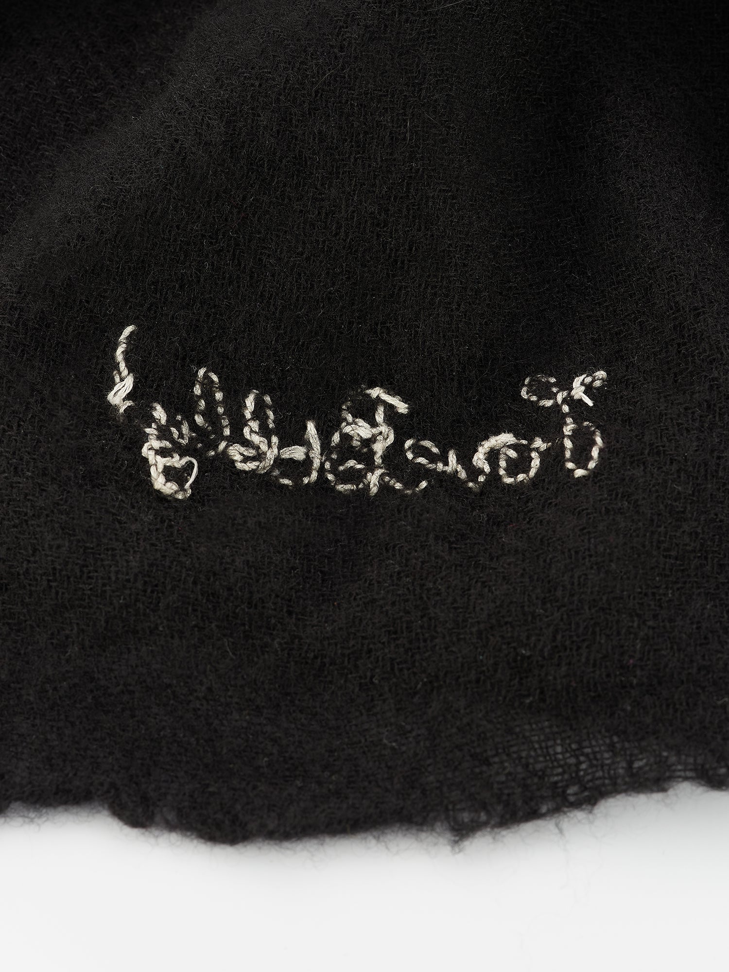 shows the back side of the black cashmere scarf where the billy logo is embroidered 